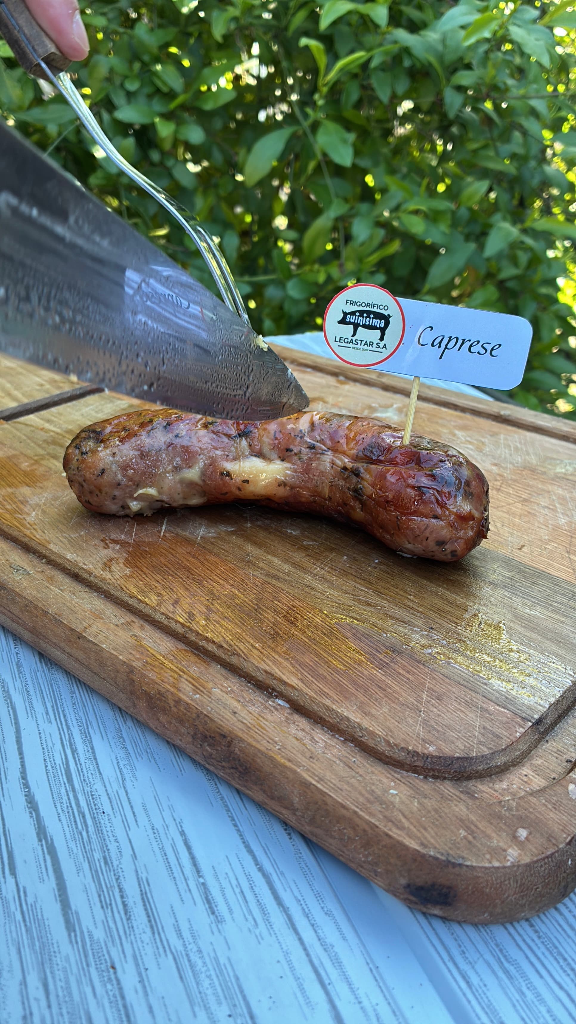 Chorizo caprese siendo cortado, queso fundido a la vista
